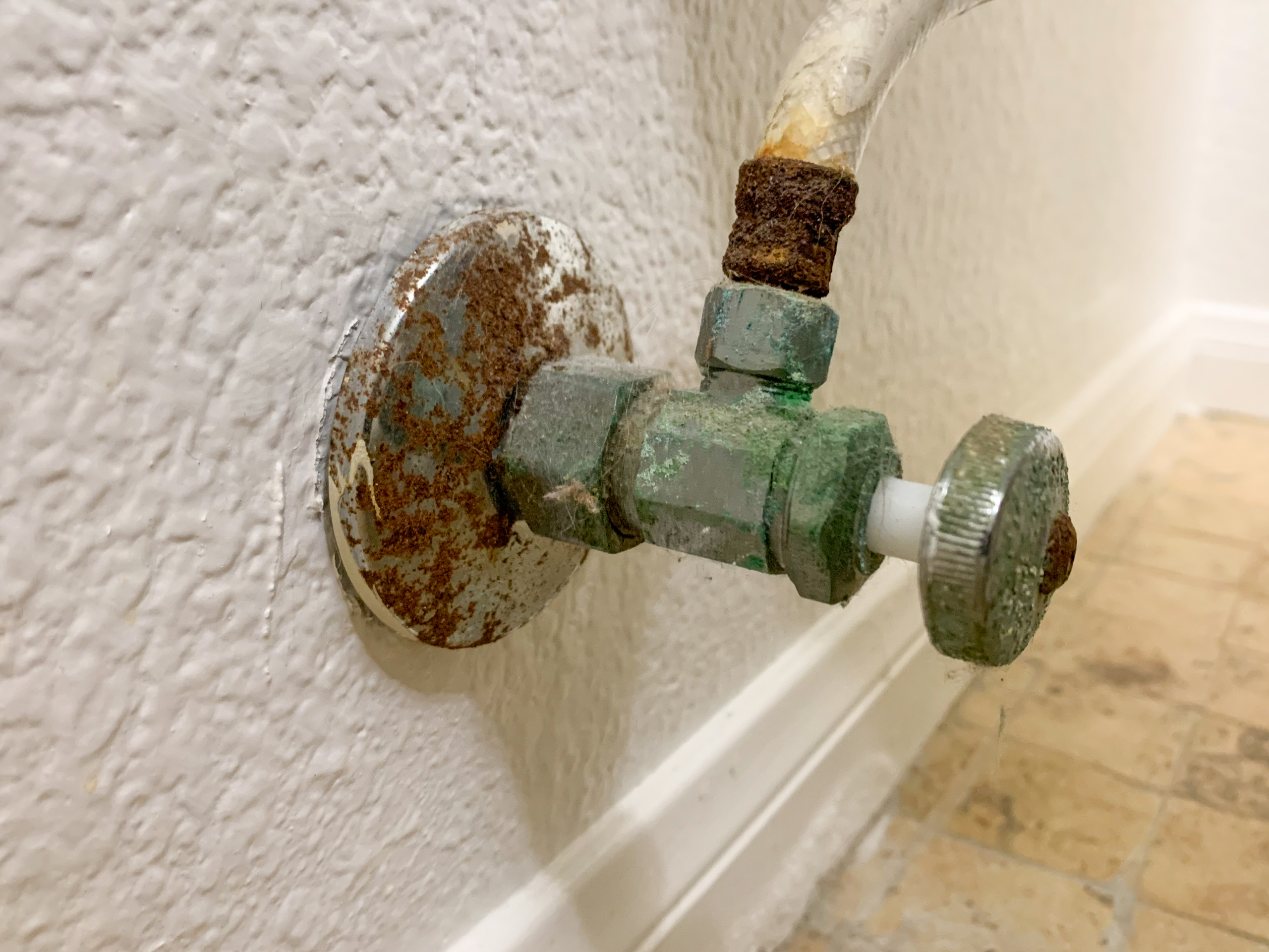 borrego-springs-plumber-angle-stop-corrosion A Borrego Springs plumber examines a corroded angle stop in a residential bathroom.
