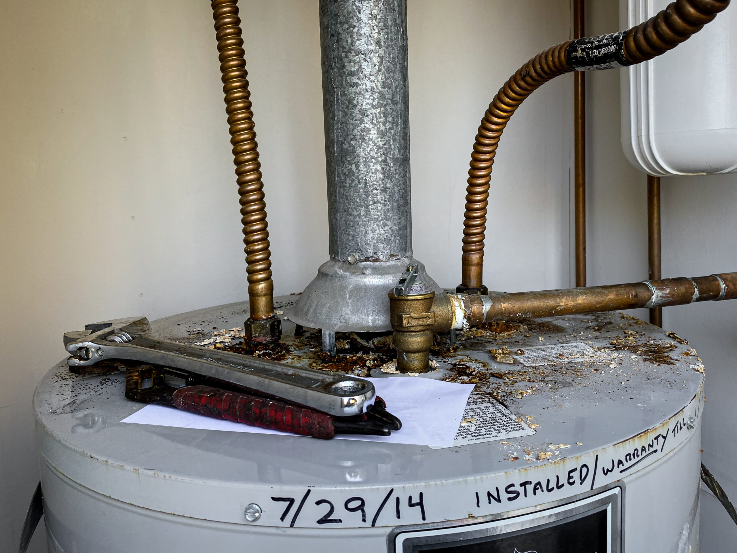 julian-plumber-water-heater-repair A plumber in Julian spots corrosion on water heater connections inside an outdoor water heater closet.