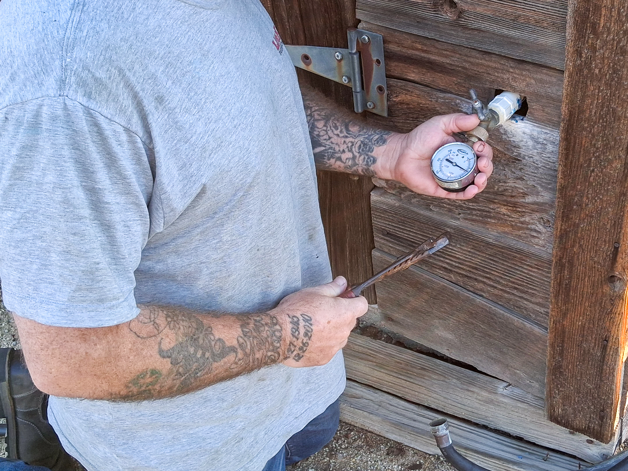 An Escondido plumber performs a water pressure test at ahose bib on a residential property.