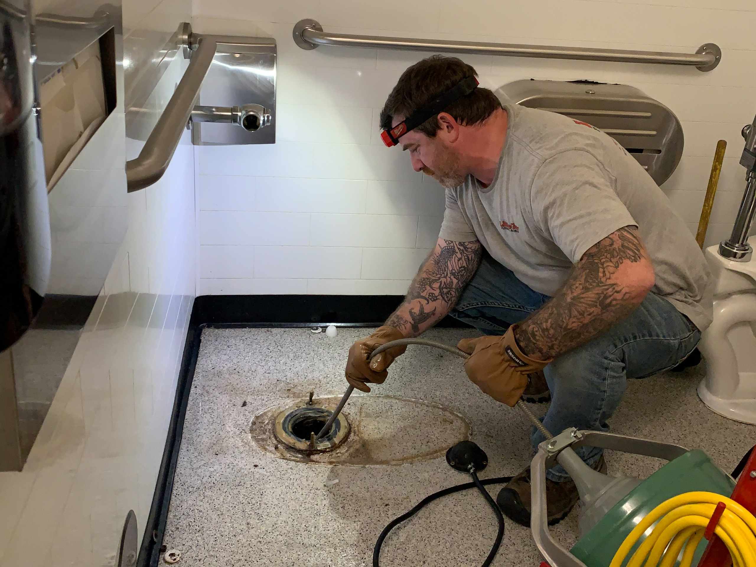 A plumber in Escondido uses a drain snake to clear a sewer line blockage.
