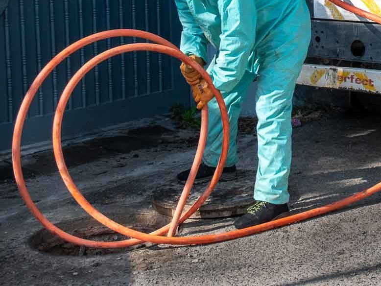 A plumber uses a hydro jetter to clean and remove roots from a main sewer line.