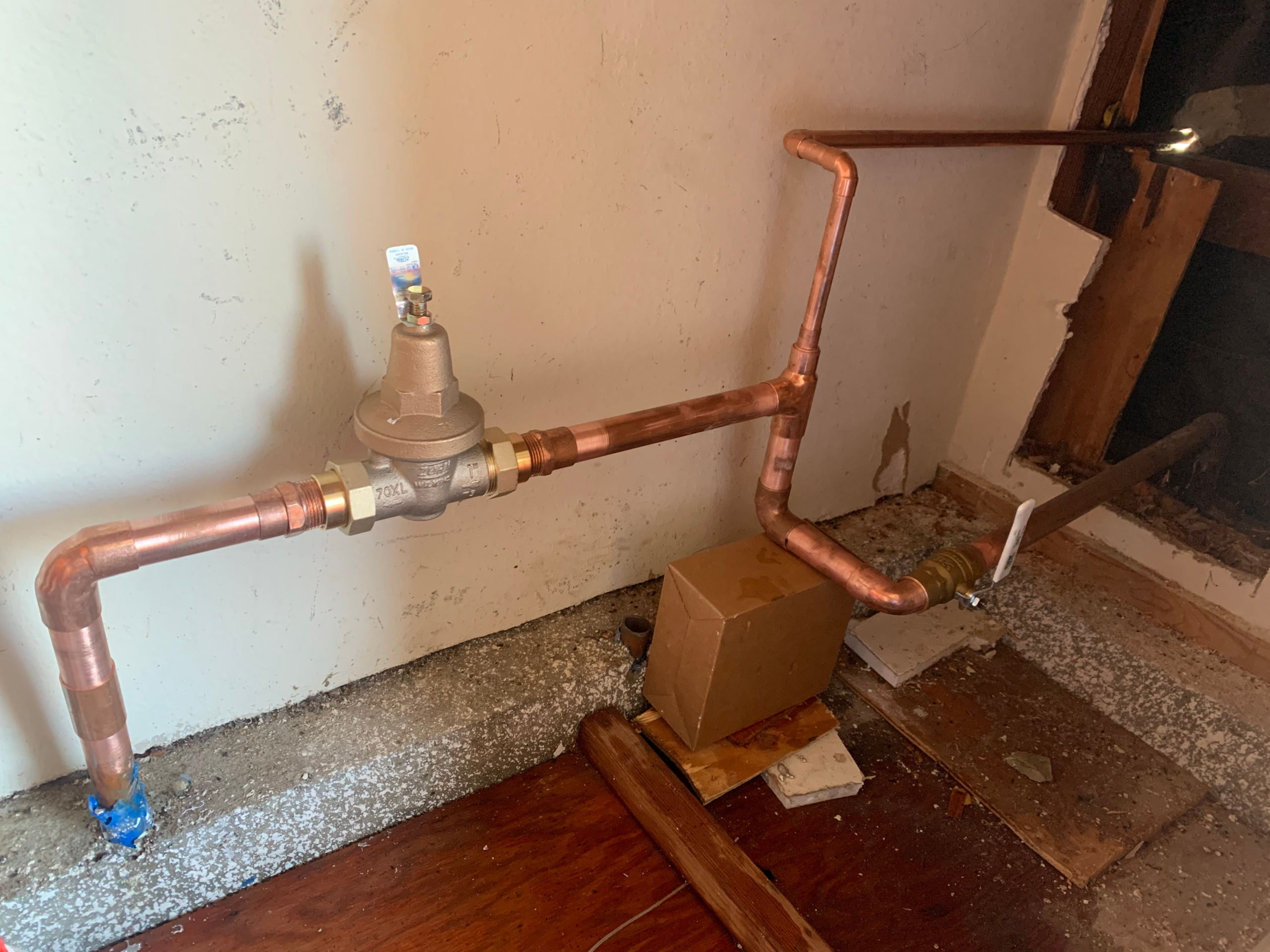 A completed copper main water service line replacement shows the piping runs into the home with a new pressure regulator.