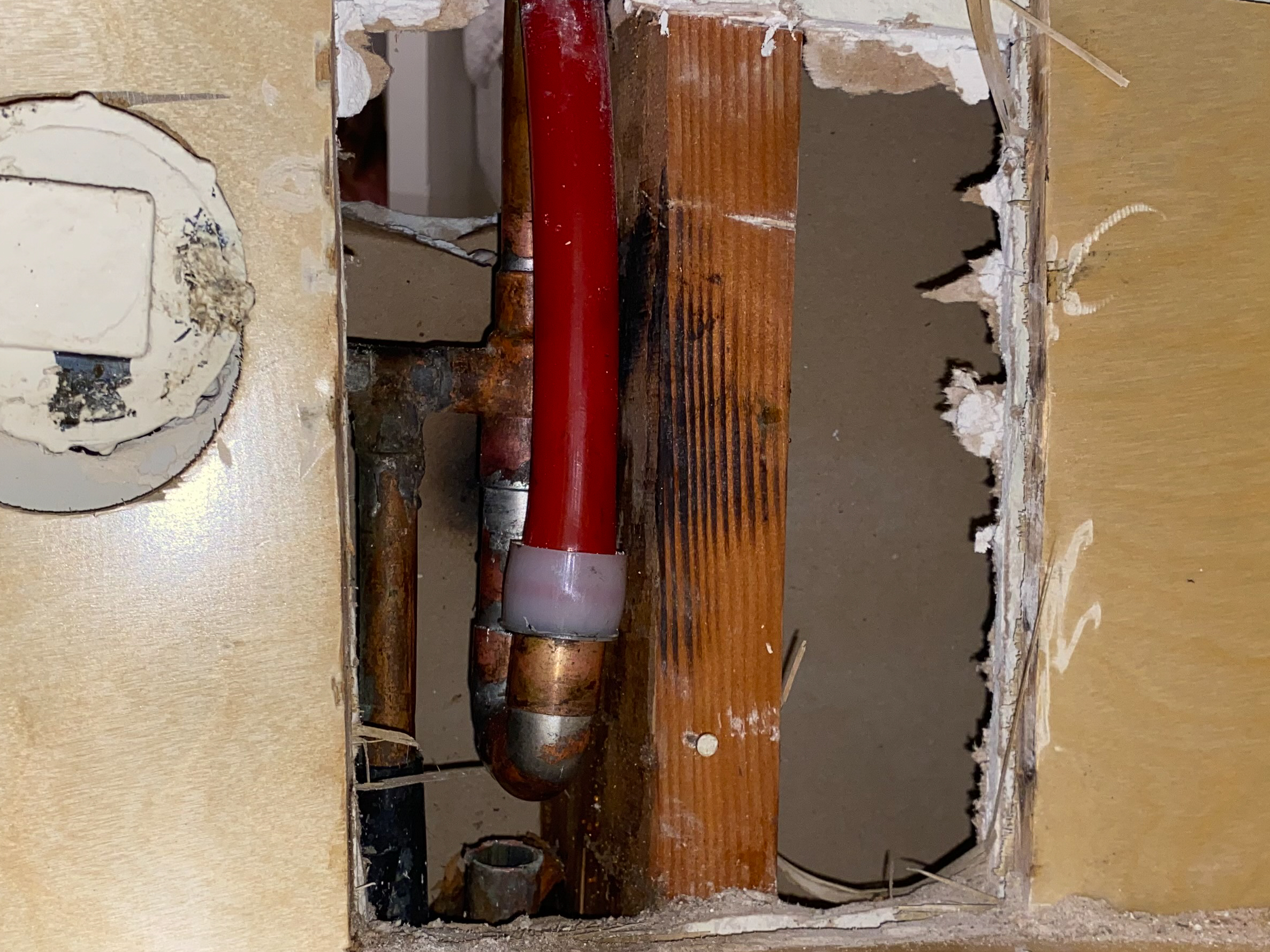 pex-reroute-in-wall A hot water line feeding a kitchen sink is rerouted using red PEX pipe.
