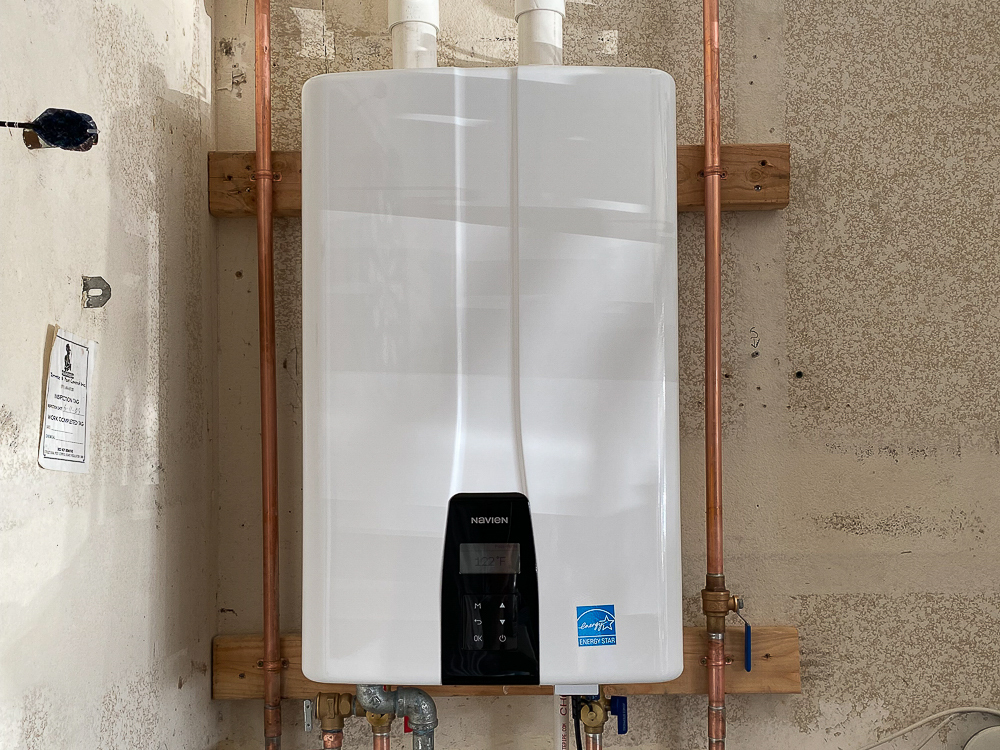 A navien tankless water heater is installed inside a residential garage, using less space than the previous tank-style unit.