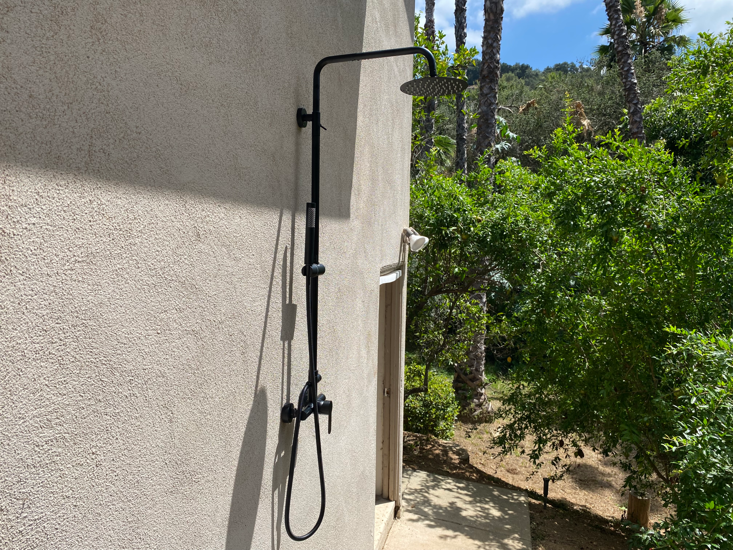 An outdoor shower is installed at an Escondido home near Citrus Ave, firmly anchored to the home's stucco exterior.