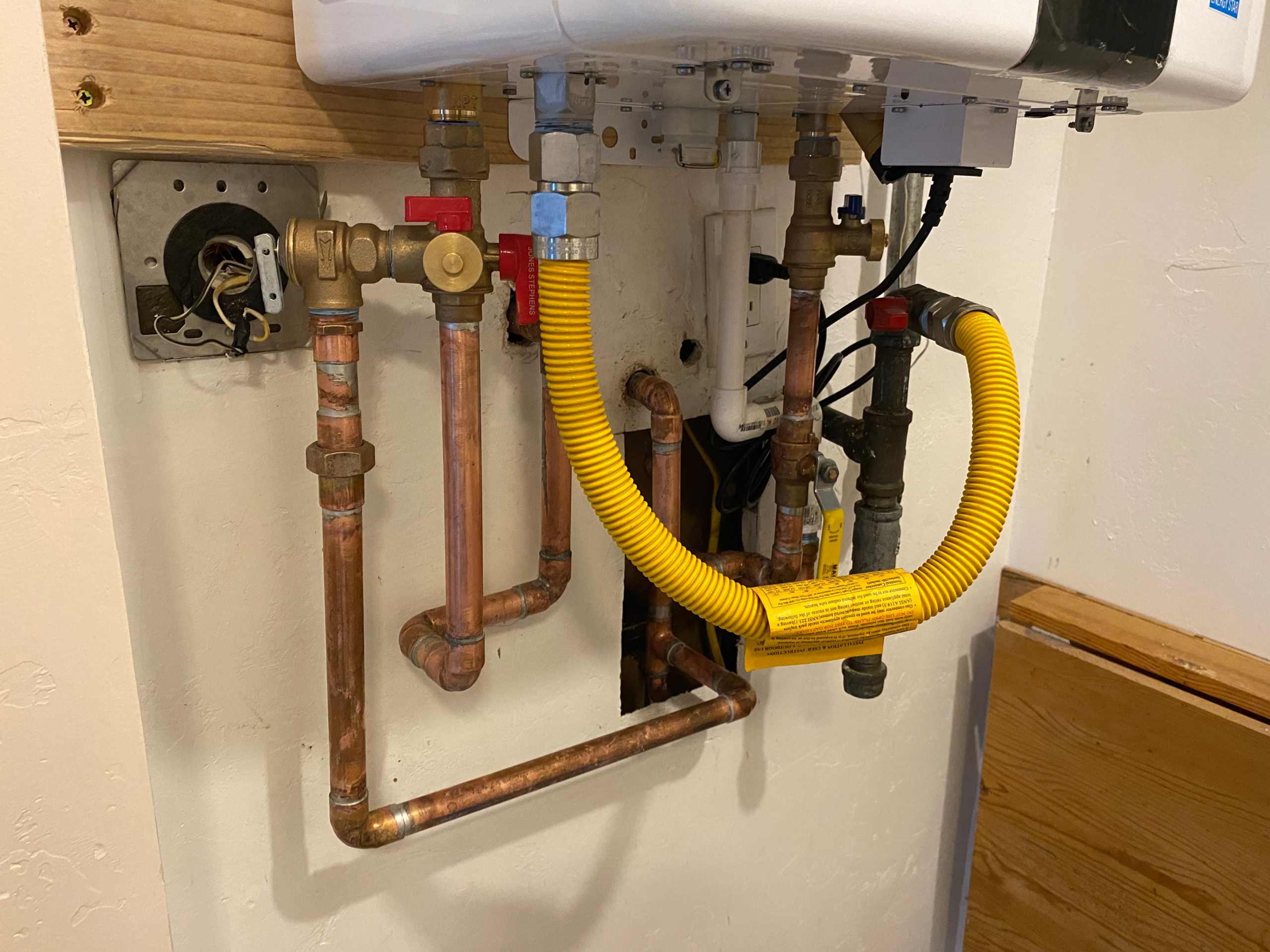 A closeup of the plumbing on a tankless water heater installation in Escondido, CA demonstrates the plumber's skill and attention to detail.